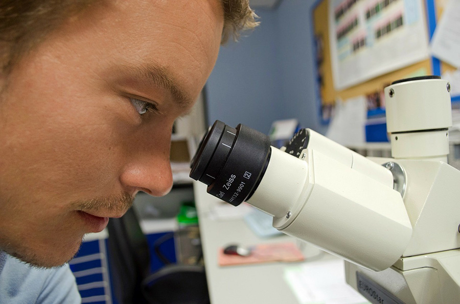 Man looking through a telescope with labcoat.